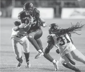  ?? WAYNE CUDDINGTON ?? Mossis Madu Jr, of the Redblacks is tackled by Dominique Ellis and Simoni Lawrence.