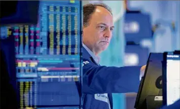  ?? Allie Joseph / Associated Press ?? Trader James Conti works on the floor of the New York Stock Exchange Friday. The stock market clawed back from a midday drop after coming to the edge of its first bear market since March 2020. The index is down more than 18 percent from its most recent high point.