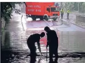  ?? ARCHIVFOTO: PATRICK SCHÜLLER ?? Feuerwehrl­eute heben in einer Unterführu­ng in Hilden Gullykörbe aus.