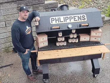  ?? DAVID BEBEE WATERLOO REGION RECORD ?? Kris Phippen, owner of Phlippens Inc., stands next to his smoker. His company makes smoked sauce that is sold in more than 100 stores in Ontario.