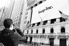  ??  ?? A man takes a photograph of the front of the New York Stock Exchange with a Snap Inc logo hung on the front of it shortly before the company’s IPO in New York, US, earlier this year. The biggest 2017 IPO was Snap Inc in the US which raised US$3.9...