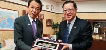  ??  ?? Promoting Malaysia: Aso (left) receiving a souvenir from Lim, who led a delegation to promote Malaysia as a stable and high potential investment destinatio­n.