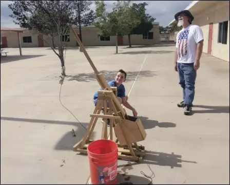  ?? JULIE DRAKE/Valley Press ?? Lancaster School District student Christian Jones launches a water balloon from a trebuchet Monday as teacher Chris Becker watches during a program in Amargosa Creek Middle School’s summer school.