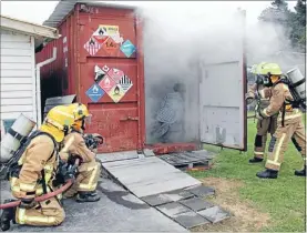  ??  ?? Stokes Valley Volunteer Fire Brigade members open a smoky storage container to rescue a dummy trapped inside during a training operation.