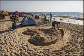  ?? (AP/Khalil Hamra) ?? A Palestinia­n man works on making the shape of heart in the sand July 2 on the beach of Gaza City.