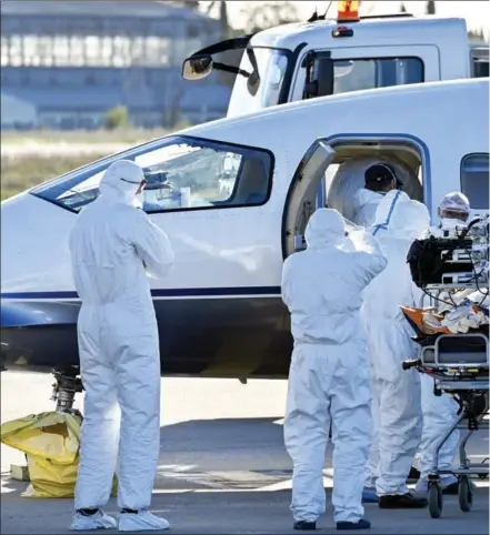  ??  ?? Medical workers escort a COVID-19 patient to an evacuation plane at Nimes-Garon Airport in Saint-Gilles, France