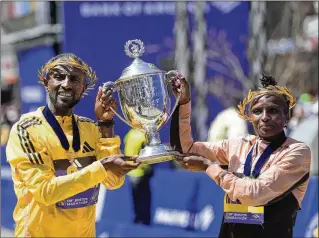  ?? PHOTOS BY STEVEN SENNE/AP ?? Men’s winner Sisay Lemma (left) of Ethiopia and women’s winner Hellen Obiri of Kenya hold up the Boston Marathon trophy during a finish-line ceremony on Monday. The race was held on the 11th anniversar­y of the bombings that killed three people and injured hundreds.