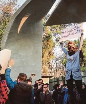  ?? [ FOTO AFP ] ?? Pelajar Iran membuat bantahan di Universiti Tehran ketika satu sesi tunjuk perasaan untuk menyuaraka­n rasa tidak puas hati dengan masalah ekonomi negara di Tehran, semalam.