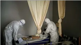  ?? EMILIO MORENATTI — THE ASSOCIATED PRESS ?? Wearing protective suits to prevent infection, mortuary workers prepare the body of an elderly person who died of COVID-19 before removing it from a nursing home in Barcelona, Spain.