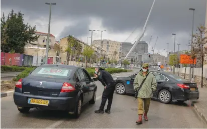  ?? (Olivier Fitoussi/Flash90) ?? POLICE OFFICERS at a temporary ‘checkpoint’ in Jerusalem yesterday check if people are not disobeying the government’s partial lockdown orders meant to curtail the coronaviru­s pandemic.