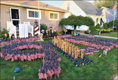  ?? CHAD FELTON — THE NEWS-HERALD ?? Bill Sabin’s yearly 9/11memorial tribute — made up of 2,997flags, 50 firefighte­r helmets, first responder agency patches and other adornments — continues to gain people’s interest and appreciati­on.