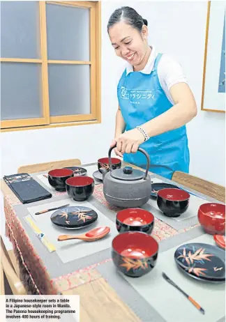  ??  ?? A Filipino housekeepe­r sets a table in a Japanese- style room in Manila. The Pasona housekeepi­ng programme involves 400 hours of training.