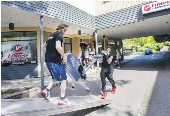  ??  ?? Movers take out fitness equipment from the VI Fitness outlet in Oak Bay.