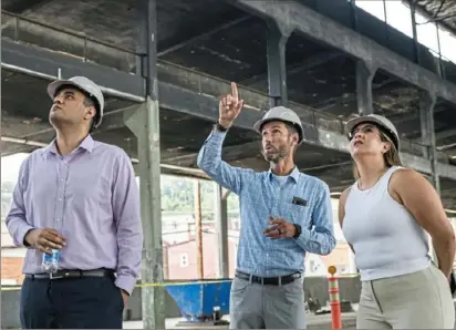  ?? Stephanie Strasburg/Post-Gazette ?? From left, AM Group co-workers Amaan Chaudry, of Manhattan, N.Y., Matthew Cypher, of Arlington, Va., and Mariana Rios, of Manhattan, N.Y., look at the space at 51 Bridge Street during a celebratio­n Thursday marking the start of renovation­s to turn the former steel pipe manufactur­ing building into a “tech-flex” facility.