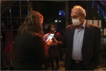  ?? MAYA ALLERUZZO — THE ASSOCIATED PRESS ?? A man presents his “green passport,” proof that he is vaccinated against the coronaviru­s, for a performanc­e where all guests were required to show proof of vaccinatio­n or full recovery from the virus, in Jerusalem.
