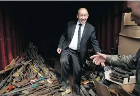  ?? JéRôME DELAY/ THE ASSOCIATED PRESS ?? French Defence Minister Jean-Yves le Drian checks out confiscate­d weapons at the airport in Bangui, Central African Republic, Wednesday. France has 1,600 peacekeepe­rs in the country.