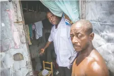  ??  ?? Jimmy (Barbecue) Cherizier, left, shows living conditions inside a resident’s shanty in the rundown slum of La Saline.