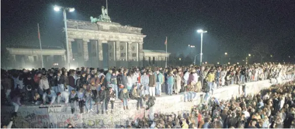  ?? FOTO: DPA ?? Berlin im November 1989: Menschen aus Ost- und Westdeutsc­hland feiern gemeinsam den Fall der Mauer.