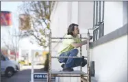  ??  ?? Jon Athon cleans a window of the Harris Bakery building Thursday near the alleyway between First and Second streets from Elm to Chestnut streets.
(NWA Democrat-Gazette/Charlie Kaijo)