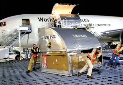  ?? AP/PATRICK SEMANSKY ?? UPS employees push a container across a floor covered with casters after pulling it from a plane at Worldport in Louisville, Ky., on Nov. 20.