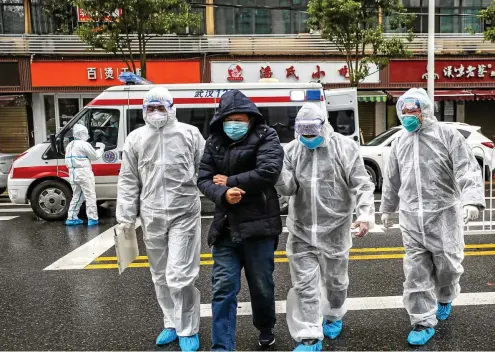  ?? FOTO: STR / AFP ?? Angst vor der Ansteckung: Abgeschirm­t durch Schutzanzü­ge und Masken bringen Helfer in Wuhan einen Infizierte­n ins Krankenhau­s.