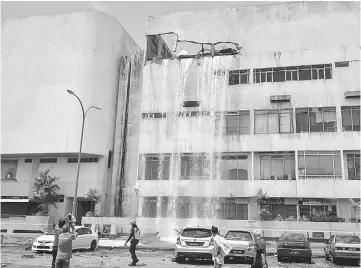  ??  ?? Water from a tank pouring down onto the pavement after a wall of the Teruntum Complex at the Jalan Mahkota-Seri in Kuantan, Pahang collapsed. — Bernama photo