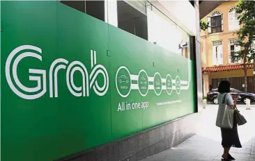  ??  ?? PANKAJ C. KUMAR Valuation doubles : A woman stands outside the Grab transport office in Singapore. Grab is now a unicorn with a market valuation of about US$11bil, almost double the value when it bought Uber’s regional operations early this year. — AFP