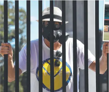  ?? Pictures: AAP. GETTY ?? NO-GO ZONE: A fan wears a gas mask outside the locked SCG gates yesterday; (top) the Aussies bat in front of empty stands and the sign that greeted ODI fans outside the ground.