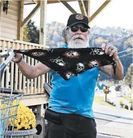  ?? KATHLEEN BATTEN/AP ?? StanleyWar­ner, ofWest Union, W.Va., holds his skull-adorned bandanna to cover his face amid the coronaviru­s pandemic. Warner says he won’t wear it unless instructed to do so.