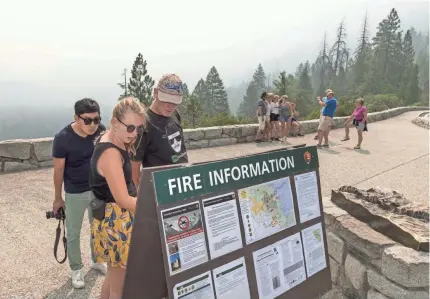  ?? RON HOLMAN/USA TODAY NETWORK ?? Smoke from the Ferguson Fire hangs in the air Tuesday as Hanna Demunck and her father, Jan Demunck, of Holland check fire maps at Tunnel View in Yosemite National Park.