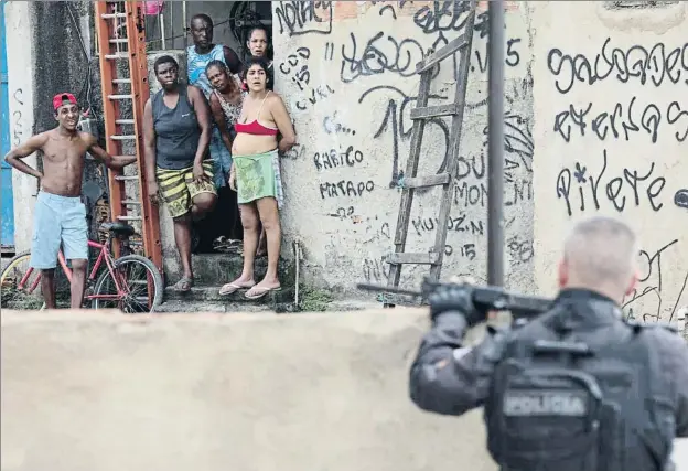  ?? LEO CORREA / AP ?? Habitantes de la favela de Ciudad de Dios, en Río, observan a la policía durante una operación llevada a cabo el pasado jueves