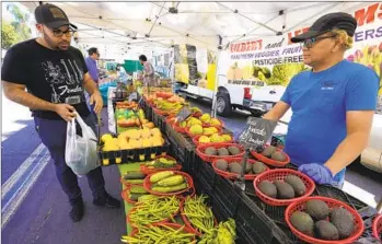  ?? NELVIN C. CEPEDA U-T PHOTOS ?? Sonny Sarzona from Gilbert and Lee Farms helps Kareem Captain at the market in Little Italy on April 13.