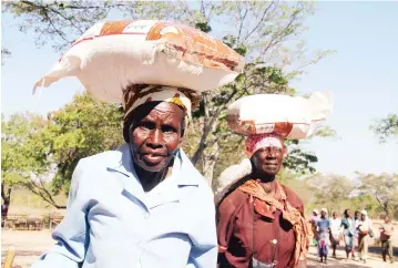  ??  ?? Gogo Esnath Kunaka (left) was among vulnerable people who received maize-meal from an non-government­al organisati­on, ROSA Internatio­nal, at Mangoro St Elizabeth School in Chikomba District, Mashonalan­d East Province, last Friday. Government has rolled out a food aid programme for the disabled, the chronicall­y ill, the destitute, child-headed households, including the elderly living with orphans. — Picture: Innocent Makawa