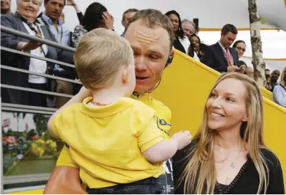  ?? — AP ?? PARIS: Tour de France winner Britain’s Chris Froome, wearing the overall leader’s yellow jersey, holds son Kellan as his wife Michelle looks on on the Champs Elysees avenue after the twenty-first and last stage of the Tour de France cycling race over...