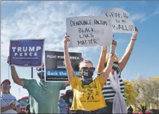  ?? MORGAN TIMMS/Taos News ?? Followed closely by a Trump supporter, counterpro­testors walk through the Trump rally holding Black Lives Matter signs Saturday (Oct. 10) outside the Taos County Administra­tion Complex, on Albright Street.