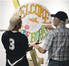  ??  ?? Student Mustafa Alabssi, left, and elder Allard Thomas figure out the placement of a sign at The Deaf Forest art installati­on.