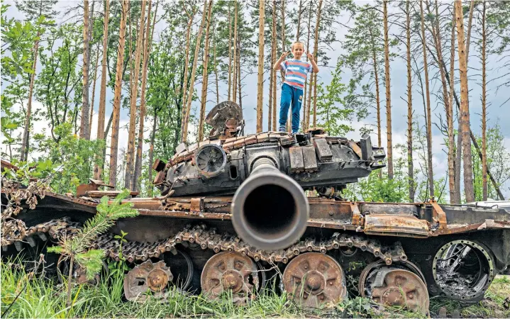  ?? ?? A local boy investigat­es the rusting hulks of Russian tanks and armoured vehicles near Bucha, a city in Ukraine’s Kyiv Oblast. Invading forces left the region at the end of March and have been accused of carrying out atrocities during the occupation