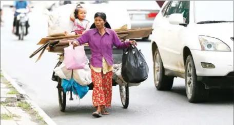  ?? HONG MENEA ?? A woman walks beside a car near Phnom Penh’s Royal Palace in 2014.