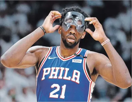  ?? JOE SKIPPER THE ASSOCIATED PRESS ?? Philadelph­ia 76ers centre Joel Embiid adjusts his mask during action Saturday against the Miami Heat.