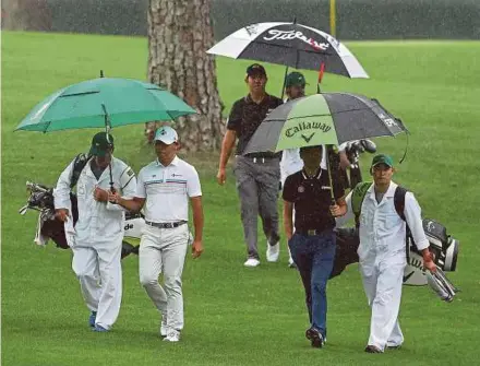  ?? AP PIC ?? Korean golfers (from left) Si Woo Kim, Byeong Hun An and Jeunghun Wang walk to the 16th green as rain moves in during their practice round for the US Masters on Monday.