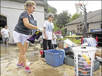  ??  ?? Sheila Siener (center) gets help Saturday from friends and family, including her sister, Julie Mabile (left), in cleaning out her flood-damaged home in St. Amant, La. Search parties in the flood zone continue going house to house looking for survivors.