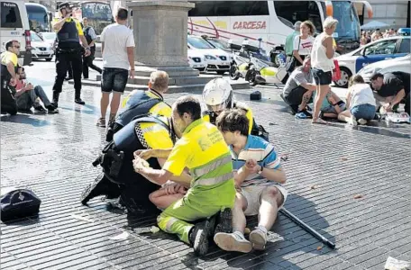  ?? Nicolas Carvalho Ochoa Getty Images ?? EMERGENCY crews and passersby assist those injured in the terrorist attack targeting pedestrian­s in Barcelona, Spain.