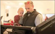  ?? LYNN KUTTER ENTERPRISE-LEADER ?? Levi Crandell, holding his 17-month-old son, Michael, votes in the March 1 Preferenti­al Primary election at Main Street Baptist Church in Farmington. Poll workers reported a steady flow of voters throughout the day with lines forming outside the...