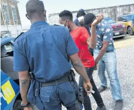  ?? RUDOLPH BROWN/PHOTOGRAPH­ER ?? Police officers escort three of five persons accused in a buggery case now before the St Ann Parish Court. When they appeared in court yesterday a new date was set for hearing on May 14.