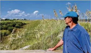  ?? ?? Tybee Island resident and consultant Alan Robertson surveys the dunes, which the city has built up and fortified with the help of grant funding. Luckily for Tybee, Robertson had grant writing experience.