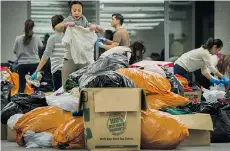  ?? ARLEN REDEKOP/PNG ?? Volunteers sort and organize clothing donated to incoming Syrian refugees inside the Telus Garden in Vancouver earlier this week.