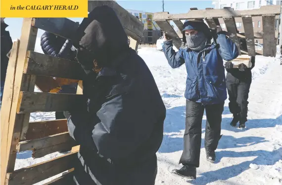 ?? RYAN REMIORZ / THE CANADIAN PRESS ?? People bring more wood to a rail blockade in St-lambert, south of Montreal, on Thursday, in solidarity with the Wet’suwet’en hereditary chiefs opposed to a gas pipeline in B.C.