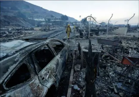  ?? AP Photo/GreGory Bull ?? Fire crews search for hot spots among destroyed homes in the Rancho Monserate Country Club community Friday in Fallbrook. The wind-swept blazes have forced tens of thousands of evacuation­s and destroyed dozens of homes in Southern California.