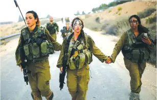  ?? (Reuters) ?? WOMEN IN AN IDF combat unit help one of their fellow soldiers during a training exercise.