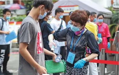  ??  ?? Students have their temperatur­es checked before entering Xinzhuang High School. — Dong Jun